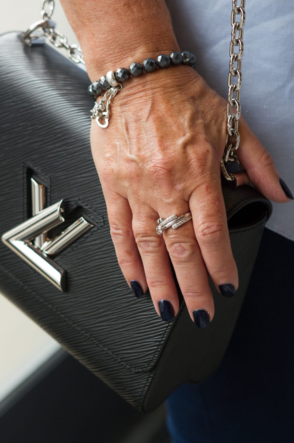 A clients nails in navy blue with an expensive hand bag